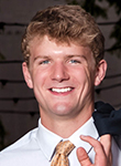 Smiling young man in a suit and tie posing for a portrait.