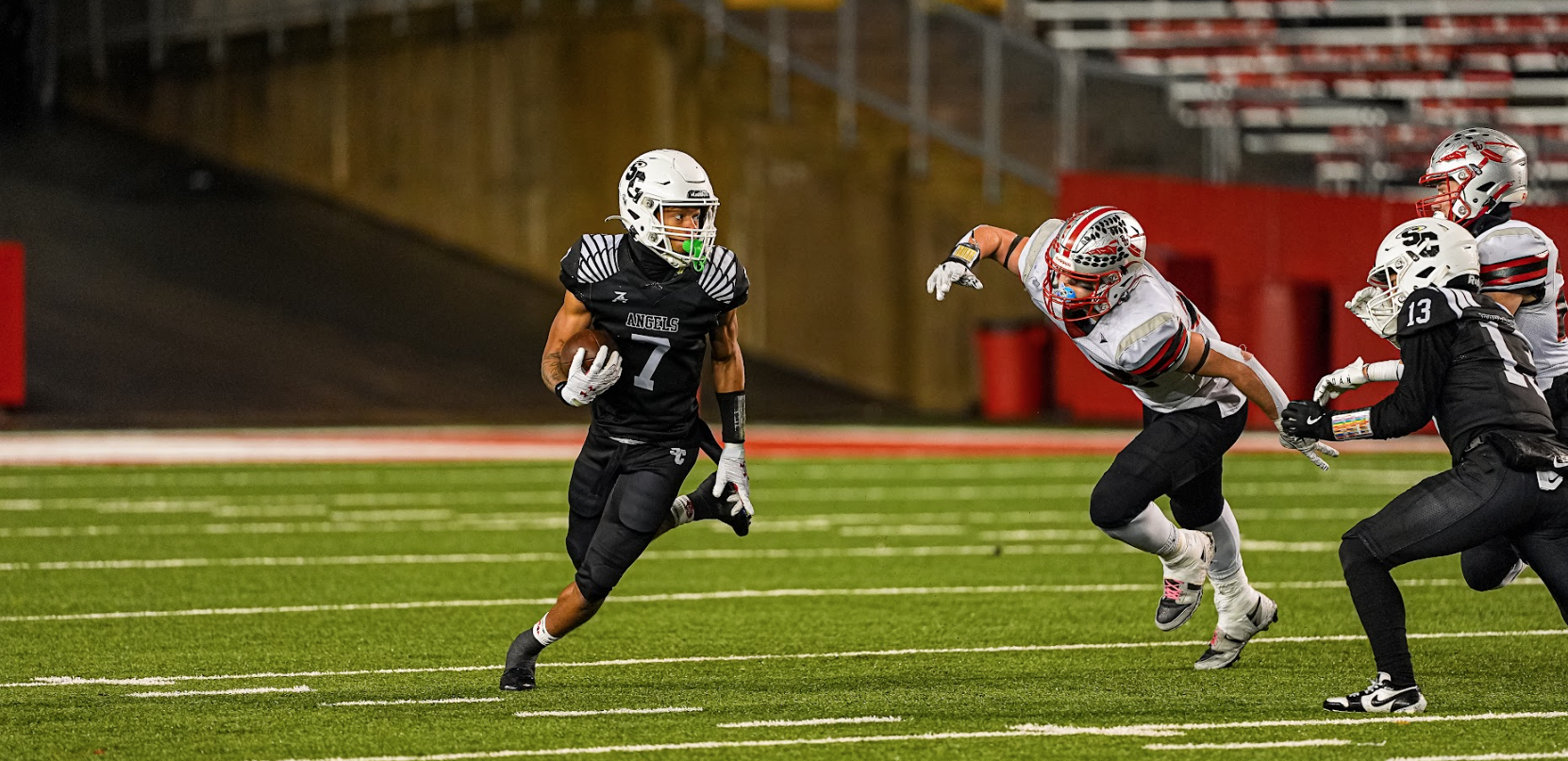a boy running from others on the field playing football