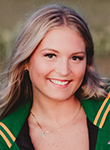 A smiling young woman poses outdoors for a portrait wearing a green graduation stole.