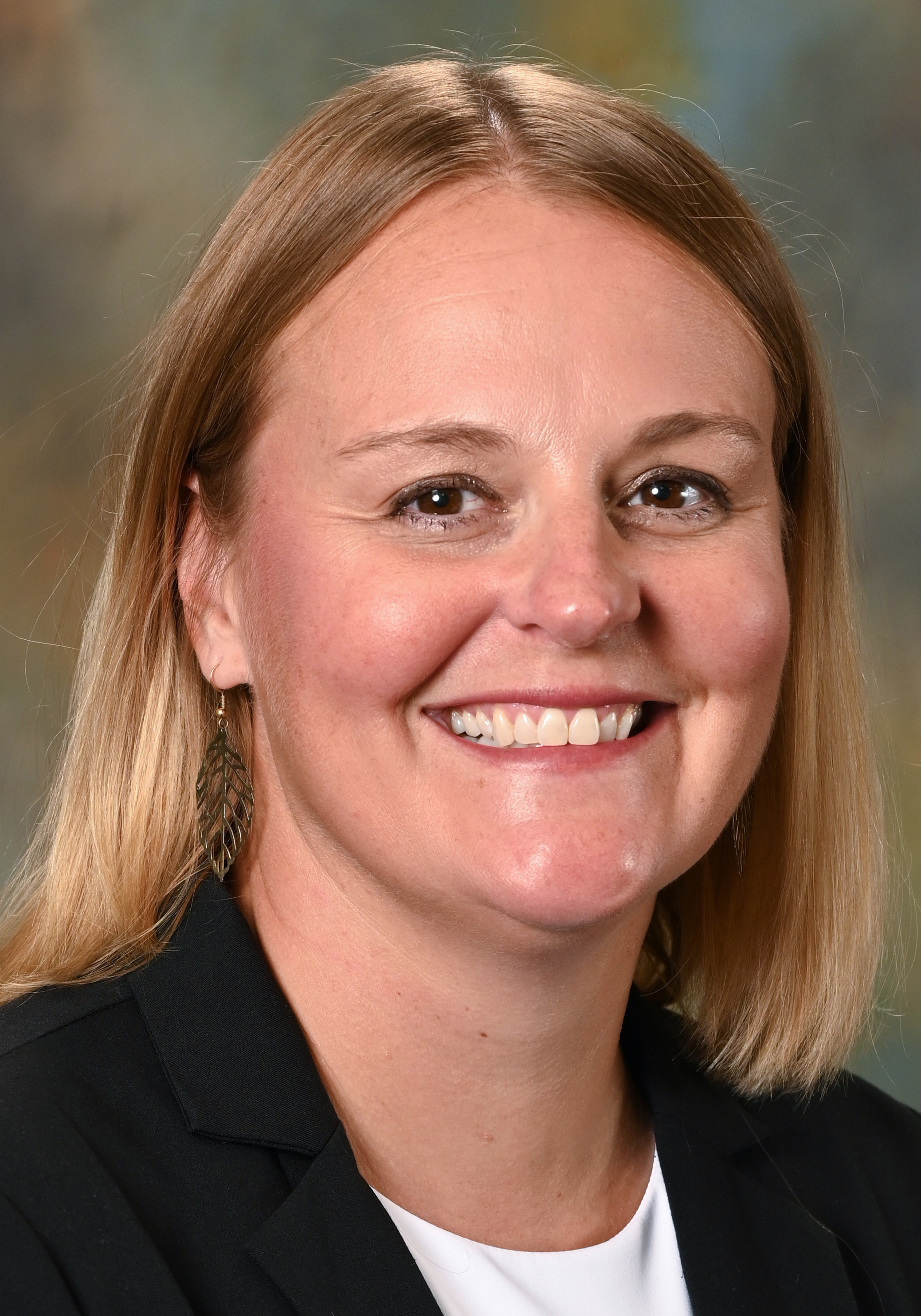 Headshot of a smiling woman with shoulder-length blonde hair wearing a black blazer and white top.
