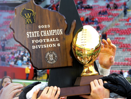 Players hold up the 2023 State Champion Football Division 6 trophy after a championship game.