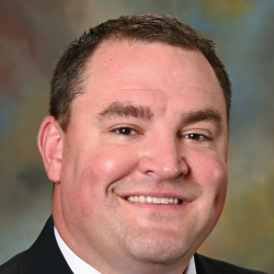 Smiling man in a suit and red tie posing for a professional headshot.